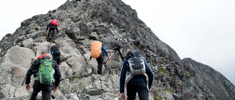 Turgåere nær en steinete fjelltopp.