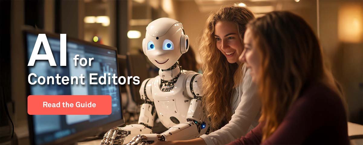 Two women and a robot sits by a computer.
