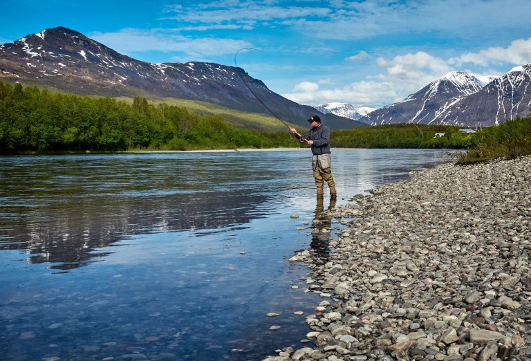 Man fishing along a riverbank.