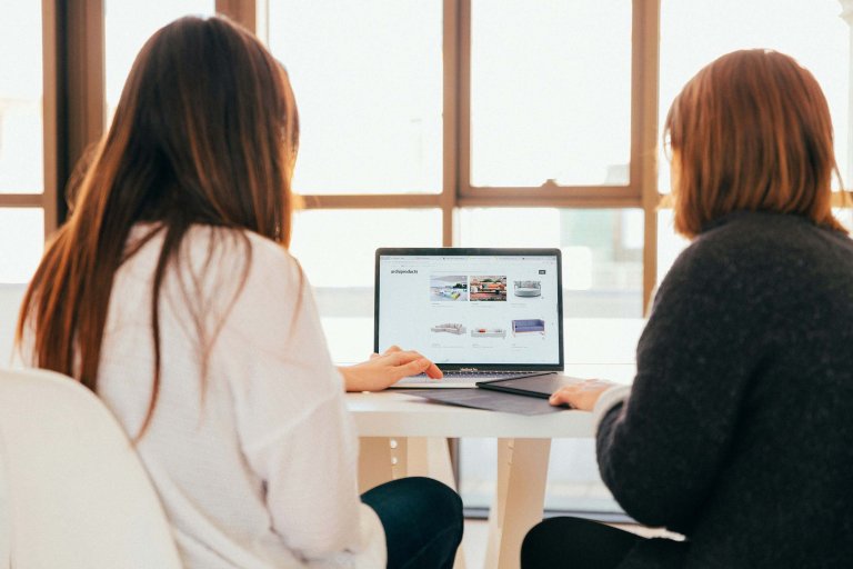 Two women sitting by a laptop.