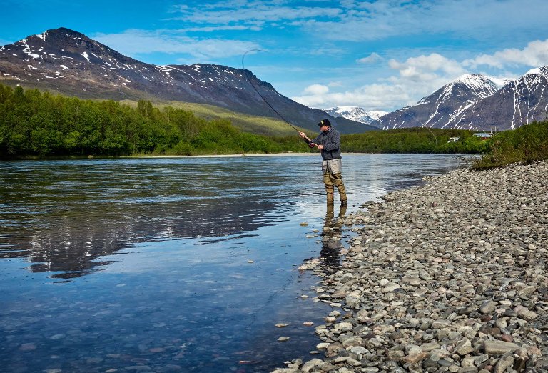 Man fishing along a riverbank.